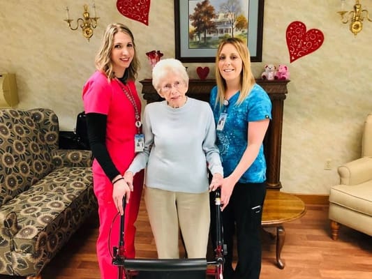 Two staff members and a resident posing for a photo in a cozy lounge area.