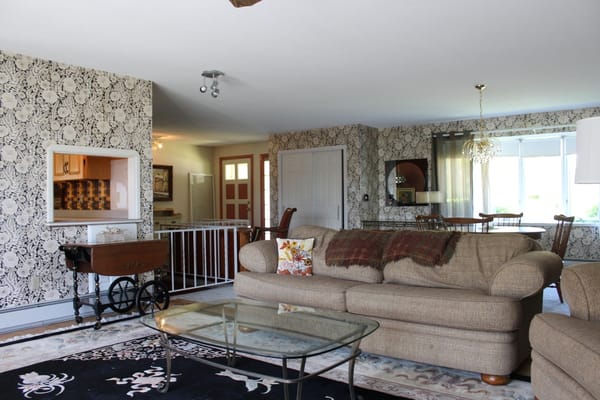 Comfortable living room with floral wallpaper and glass coffee table.