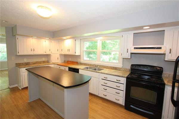 Bright kitchen with white cabinets and black appliances