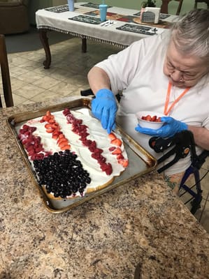 A resident decorating a dessert with fruits in the kitchen