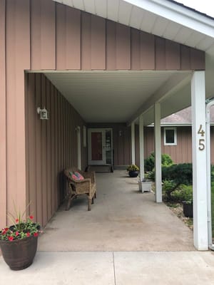 Entrance of a residential living facility with flowers and seating