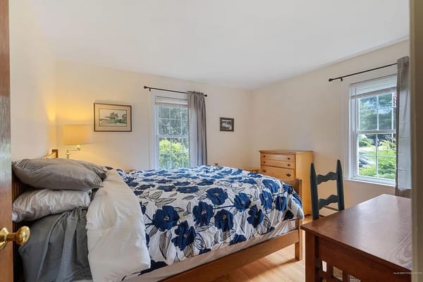 Bright bedroom with floral bedding and wooden furniture