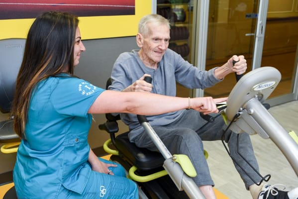 Staff assisting resident with fitness equipment