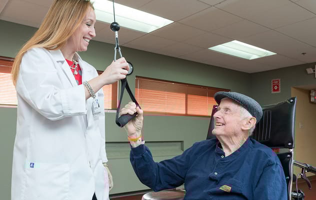 Therapist assisting a resident with exercise equipment