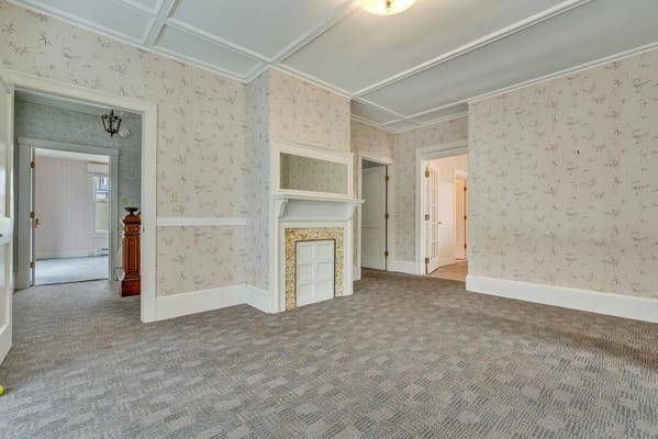 Bright living room with patterned wallpaper and a fireplace.