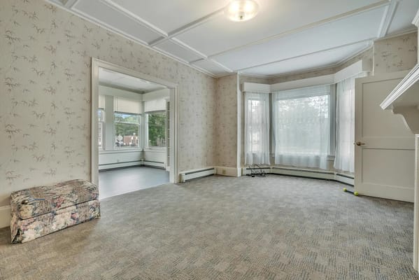 Spacious living room with natural light and floral wallpaper