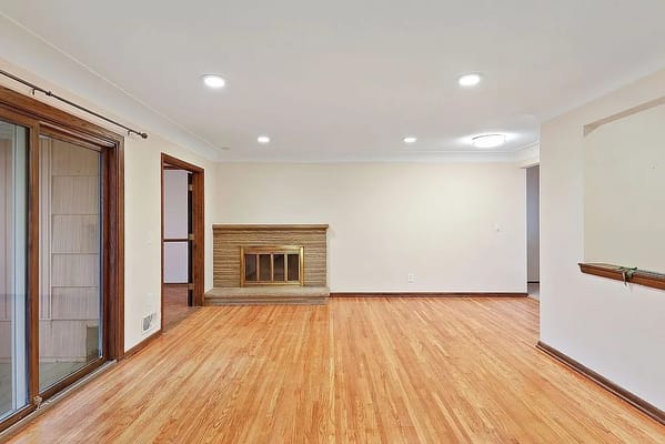 Bright and spacious living room with hardwood flooring and a fireplace.