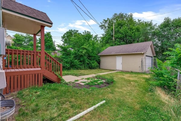 View of the backyard with grass, pathway, and shed.