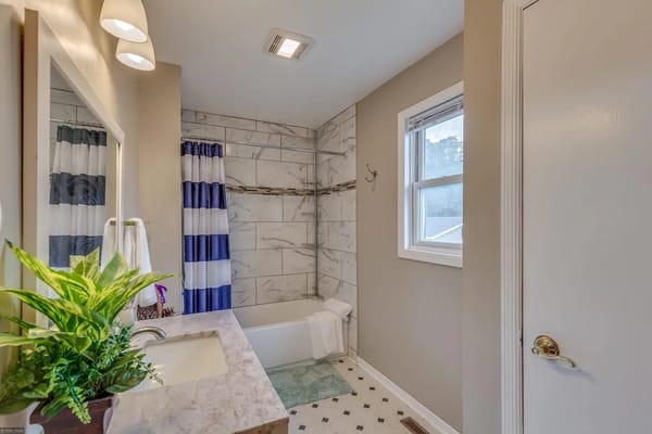 Stylish bathroom with marble tiles and striped curtains