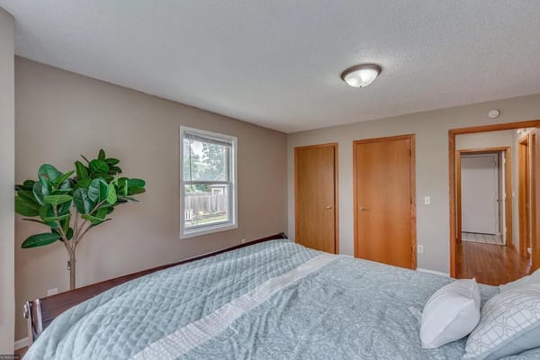 A neatly arranged bedroom with a bed, decorative pillows, and a window.