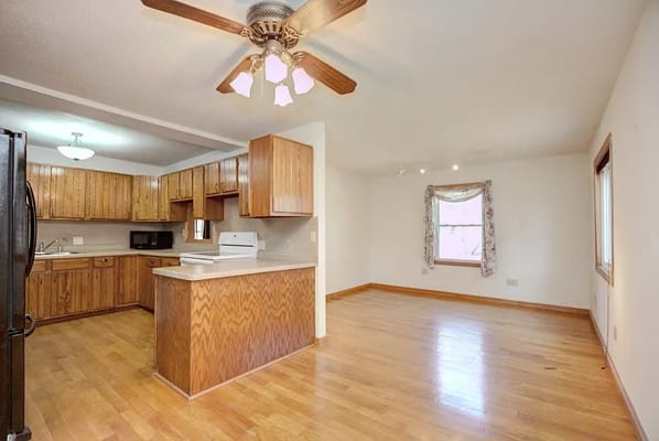 Open kitchen and living space with wooden cabinets and flooring.