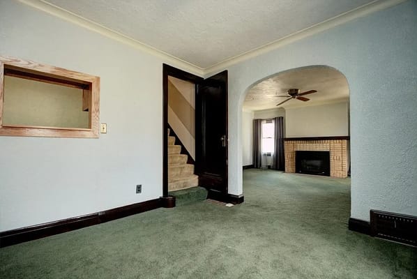 Spacious living room with green carpet and fireplace