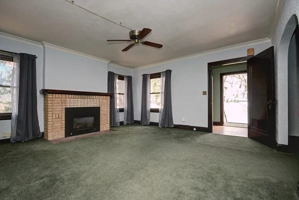 Spacious living room with green carpet and fireplace