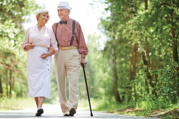 Elderly couple walking in a sunny outdoor setting