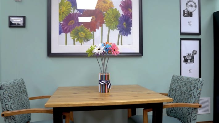A cozy common area with a wooden table and flowers