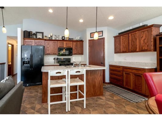 A modern kitchen with an island, wooden cabinets, and appliances.