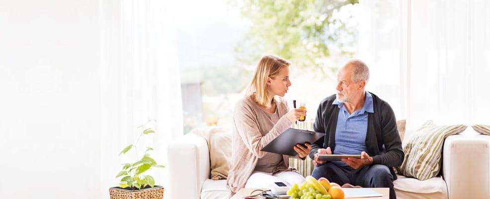 A caregiver discussing with a senior resident in a cozy interior.