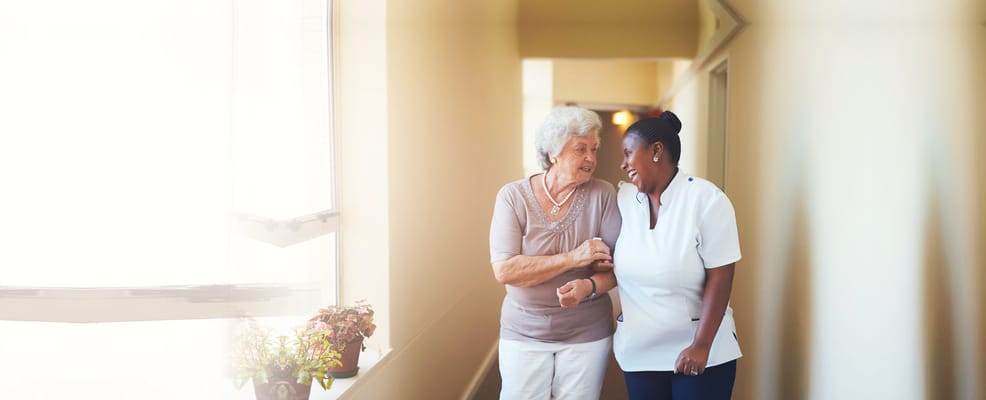 A caregiver helping a resident in a hallway