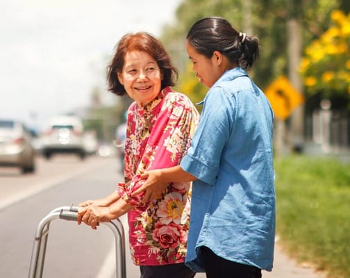 A caregiver assisting an older woman outdoors