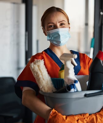 Staff member holding cleaning supplies in an indoor setting