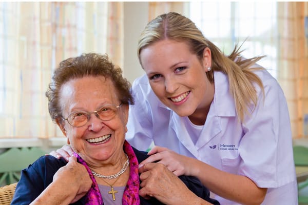 A caregiver and resident smiling together in an indoor setting