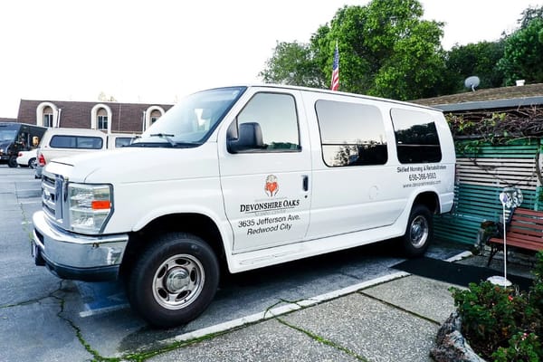 White transport van with Devonshire Oaks branding parked outside.