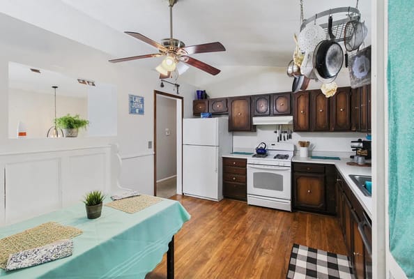 A well-lit kitchen with a table and various kitchen appliances