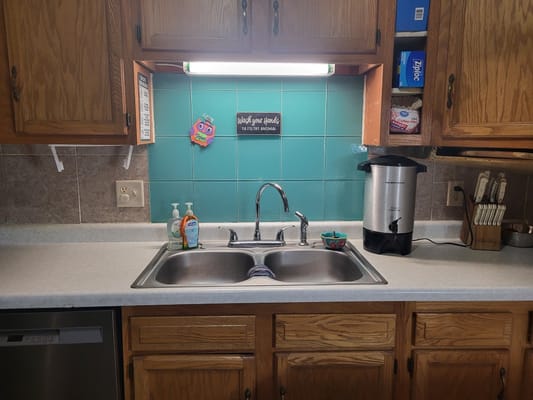 Clean kitchen sink with turquoise backsplash and amenities