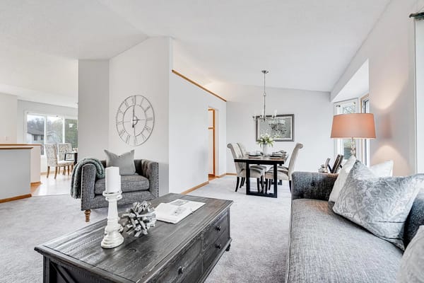Cozy living room featuring a grey couch, coffee table, and dining area.