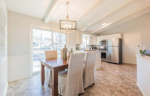 Bright kitchen with dining table and stainless steel appliances.