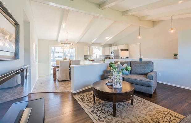 A cozy living room with a gray couch and a round table with flowers.