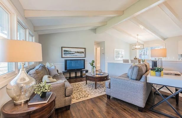 A cozy living room with gray sofas, a round table, and a TV