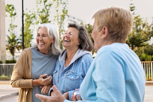 Three women laughing together in an outdoor space