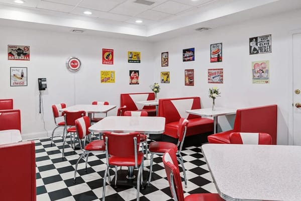 A retro-themed dining area with red and white seating and vintage wall decorations.