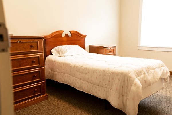 Single bed with wooden furniture in a well-lit room