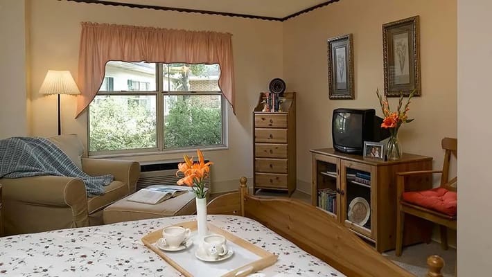 A cozy resident room with a bed and seating area