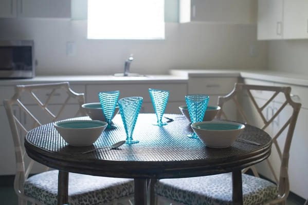 A dining table set with blue glasses and bowls in a bright kitchen setting.