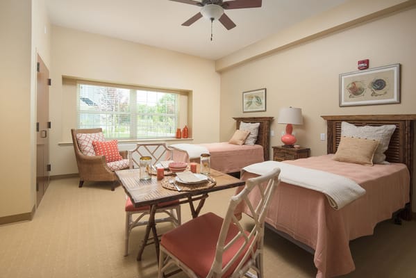 A shared bedroom with two beds, a seating area, and a dining table.