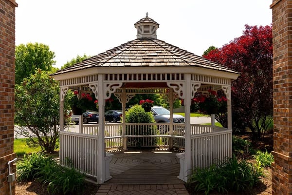 White gazebo surrounded by greenery and flowers