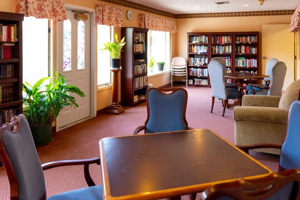 Bright library area with bookshelves, seating, and plants.