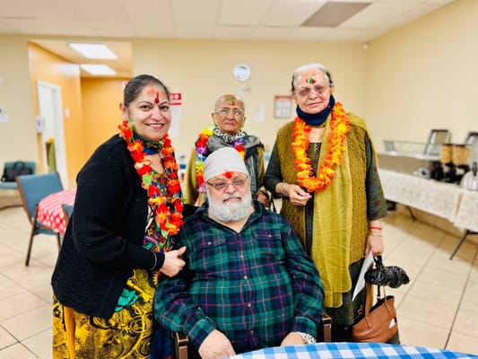 Four seniors celebrating with floral leis in a dining area
