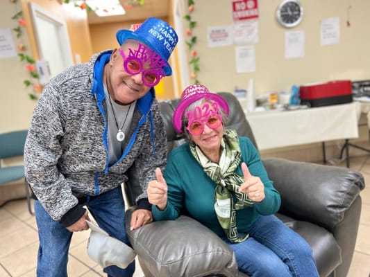 Two seniors celebrate New Year’s wearing festive hats and glasses