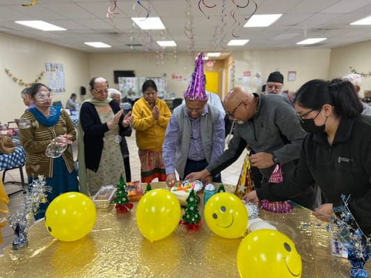 Group celebration with balloons and cake at Premier Social Adult Day Services