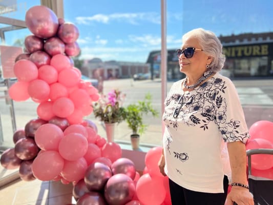 Smiling older woman standing next to a balloon decoration.