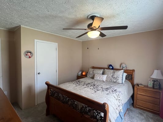 Cozy private bedroom with a wooden bed and ceiling fan