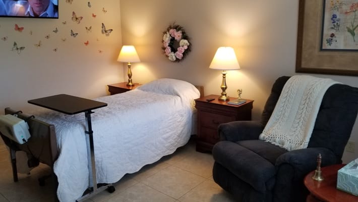 Cozy bedroom with a bed, side tables, and a recliner in Southern Living Specialty Care