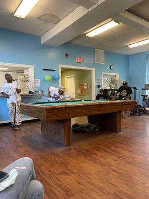 Residents engaging in a game of billiards in a common area