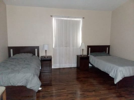 A shared bedroom with two beds, nightstands, and a window.