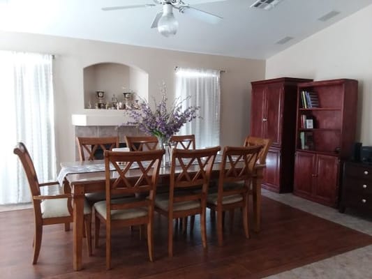 Spacious dining room with a wooden table and chairs, featuring a vase of flowers.
