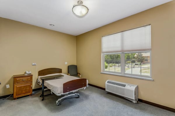 Spacious bedroom with a hospital bed and window at Family Health & Rehab.